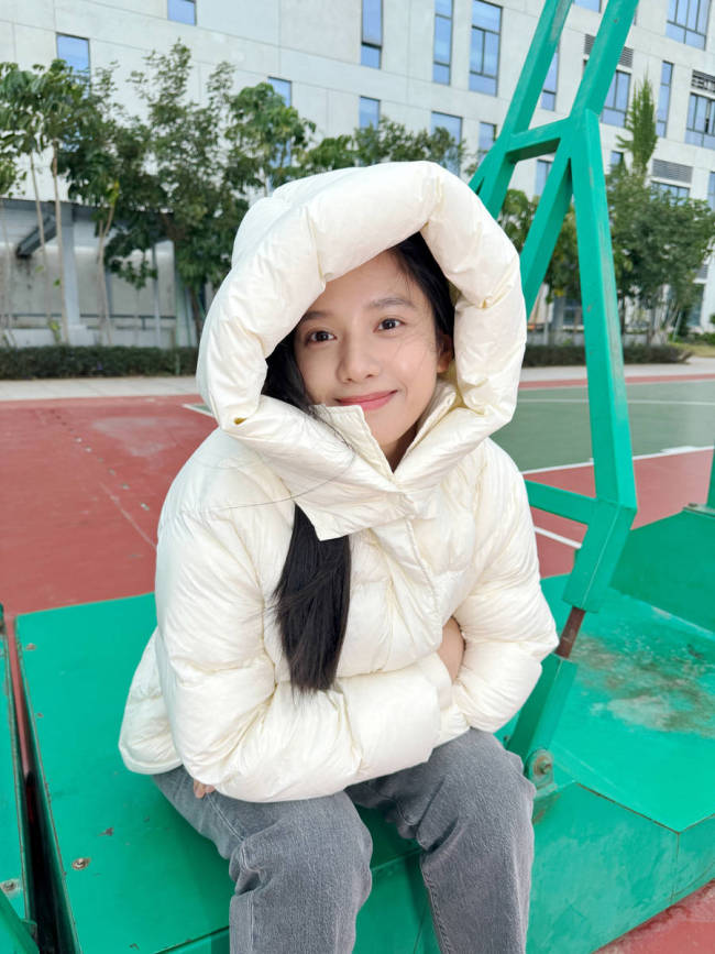 张婧仪身穿羽绒服笑容灿烂 双手托腮显俏皮