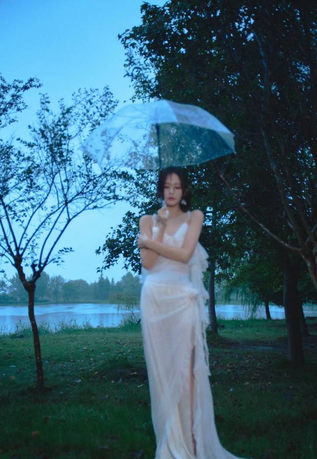 李一桐穿白色吊带裙身材窈窕 雨中撑伞氛围感十足